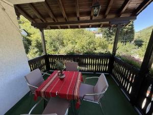 un tavolo rosso e sedie su una terrazza in legno di Къща за гости Сияйна Зора a Plachkovtsi