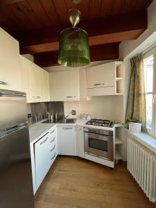 Una cocina con gabinetes blancos y una lámpara de araña verde. en Residenza l'Antico Borgo, en Trieste 17 fotos más