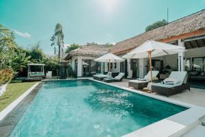 a swimming pool with chairs and umbrellas next to a house at CALA NINETA Private Villa in Dalung