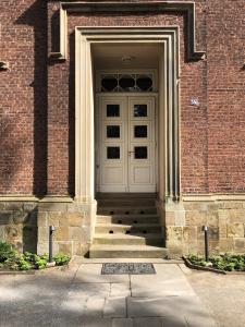 - une porte blanche sur un bâtiment en briques avec des escaliers dans l'établissement Das Ministerhaus - historisches Anwesen für Gruppen und Seminare, à Bergkamen