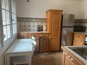 a kitchen with a white table and a refrigerator at Domaine Chapelle in La Chapelle-la-Reine