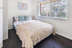 a bedroom with a bed with a blanket and a window at Yarralumla Apartment Stay Queen Bed and Sofa Bed Free Parking in Yarralumla +3 photos