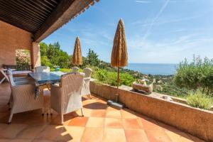 a patio with a table and chairs and a view of the ocean at Villa Bellevue Avec Vue Mer in Saint-Peïre-sur-Mer