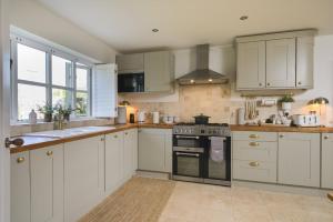 a kitchen with white cabinets and a stove top oven at Beautiful Home & Garden in Somerset Countryside in East Lydford