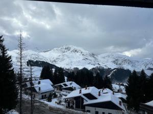a snow covered mountain with houses and snow covered roofs at Casa Vacanza in Prato Nevoso
