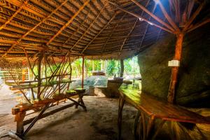 a room with a bench and a thatched roof at Wooden Eco Cottage in Katiyawa