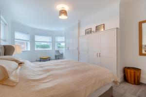 a white bedroom with a large bed and windows at Meri Rauha in Felixstowe