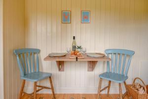 a table with two blue chairs and a bottle of wine at The Orchard Hut in Burnham Market +21 photos