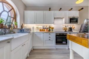 a white kitchen with white cabinets and a window at The Ostlery in Tunstead +24 photos