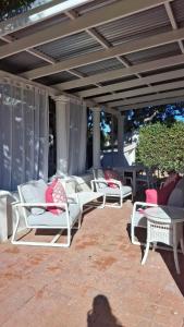 eine Gruppe weißer Stühle auf einer Terrasse in der Unterkunft La Mode Garden Cottage in Paarl