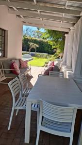 ein weißer Tisch und Stühle auf einer Terrasse in der Unterkunft La Mode Garden Cottage in Paarl