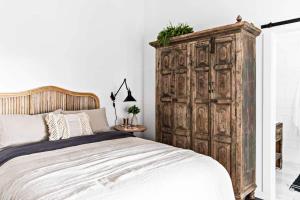 a bedroom with a large wooden cabinet next to a bed at Soul of Gerringong Cottage in Gerringong