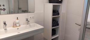 ein weißes Badezimmer mit Waschbecken und Spiegel in der Unterkunft FeWo Friedrichshafen in Friedrichshafen + 7 Fotos