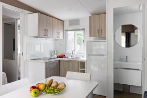 a white kitchen with a bowl of fruit on a table at New Campsite in Camping Ca' Savio in Cavallino-Treporti +100 photos