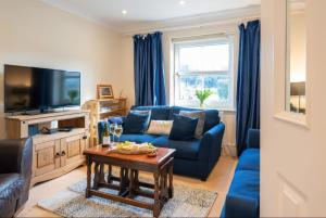 a living room with a blue couch and a tv at Beach House in Bembridge