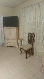 ein Zimmer mit einem Stuhl, einer Kommode und einem Fernseher in der Unterkunft Alojamiento OLSI in Torreón