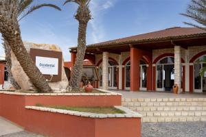 a building with palm trees in front of it at Occidental Boa Vista Beach in Rabil