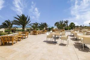 a restaurant with tables and chairs on a patio at Occidental Boa Vista Beach in Rabil