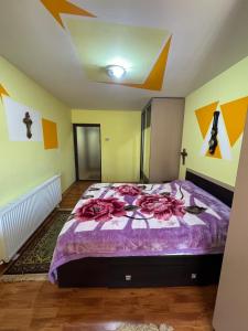 a bedroom with a bed with a purple comforter at Mica casă roșie in Cîmpulung