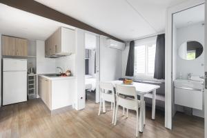 una cucina e una sala da pranzo con tavolo e sedie bianchi di New Campsite in Cesenatico Camping Village a Cesenatico