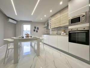 a white kitchen with a table and a microwave at LianHome b&b "Terrazzino" in Lucera