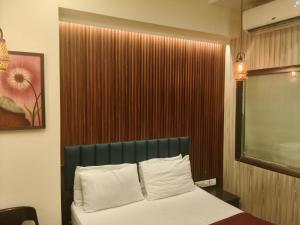 1 dormitorio con 1 cama con cabecero verde y ventana en Vaishnavi Inn, en Solapur