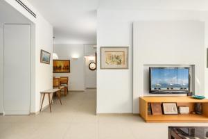 a living room with white walls and a tv on a wall at Chic Bright Urban Escape by Sea N Rent in Tel Aviv