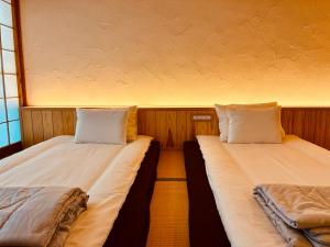 two beds sitting next to each other in a room at のどかな風景と綺麗な星空の宿 "キノイロ ミニマル" "Kinoiro Minimal" in Ainan