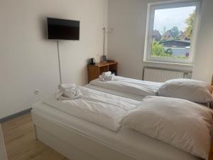zwei weiße Betten in einem Zimmer mit Fenster in der Unterkunft M2 Rooms in Lübeck