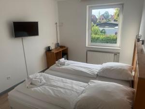 zwei Betten in einem Zimmer mit Fenster in der Unterkunft M2 Rooms in Lübeck