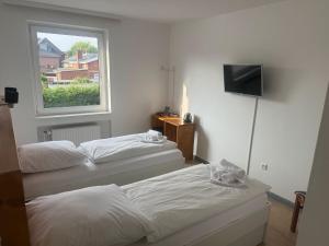 zwei Betten in einem Zimmer mit Fenster und Fernseher in der Unterkunft M2 Rooms in Lübeck