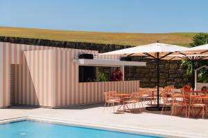a pool with tables and chairs next to a building at Crowne Plaza - Caparica Lisbon in Costa da Caparica