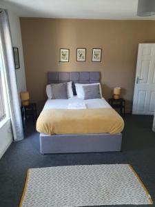 a bedroom with a bed and two tables and a window at Lovely 5 Bedroom Home w Garden near Northampton in Earls Barton