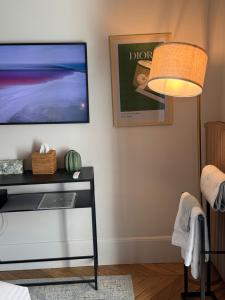 sala de estar con TV y mesa con lámpara. en Chambre au Jardin, en París