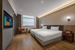 a bedroom with a large white bed and a tv at 上海浦东机场华美达安可酒店-免费提供24小时浦东机场班车十分钟到达候机楼出发层 in Shanghai