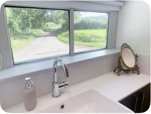 a kitchen sink with a mirror and a window at The Hayloft- Cosy cottage in Mendip AONB in South Widcombe