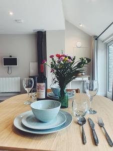 a table with a bowl and plates and wine glasses at The Hayloft- Cosy cottage in Mendip AONB 