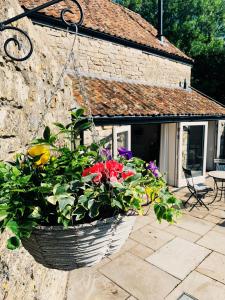 a basket of flowers hanging from the side of a house at The Hayloft- Cosy cottage in Mendip AONB 