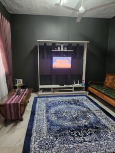 a living room with a tv and a large rug at ROSH'Homestay in Sungai Pelik