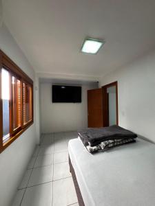 a bedroom with a bed and a flat screen tv at Casa disponível in Ibirubá