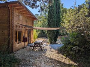 a picnic table and a hammock next to a cabin at La cabane des Pachous in Tourves