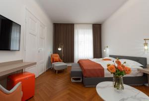 a hotel room with a bed and a vase of flowers on a table at Elias Residence Vienna in Vienna