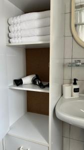 a bathroom with a sink and a shelf with towels at Entire Villa, free breakfast, free parking in Veldhoven
