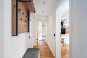 a hallway leading to a kitchen with white walls and wooden floors at Ferienwohnung Kurparkblicksauerland in Lennestadt