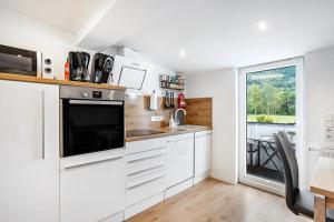 a kitchen with white cabinets and a large window at Ferienwohnung Kurparkblicksauerland in Lennestadt