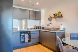 a kitchen with stainless steel appliances and a table at Stylish City Apartment with Juliette Balcony, Retro Games & Fast WiFi in Liverpool