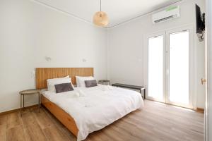 a white bedroom with a large bed and a large window at Muse Studios & Apartments Aegina in Agia Marina Aegina