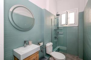 a bathroom with a sink and a mirror and a toilet at Muse Studios & Apartments Aegina in Agia Marina Aegina