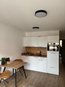 a kitchen with white cabinets and a wooden table at Queen Apartment in Metzingen