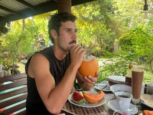 a man sitting at a table with a drink at Yaye Guest House in Tissamaharama